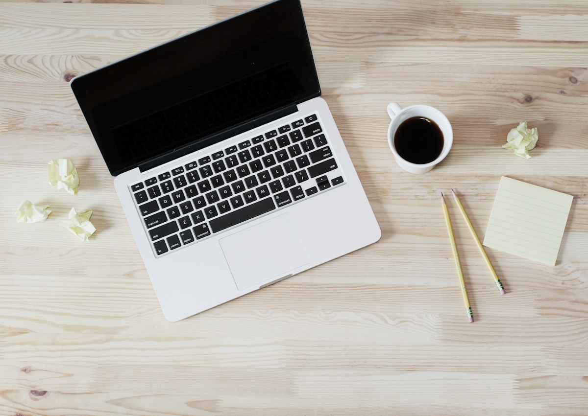 Laptop, coffee, and notes on a desk for website planning